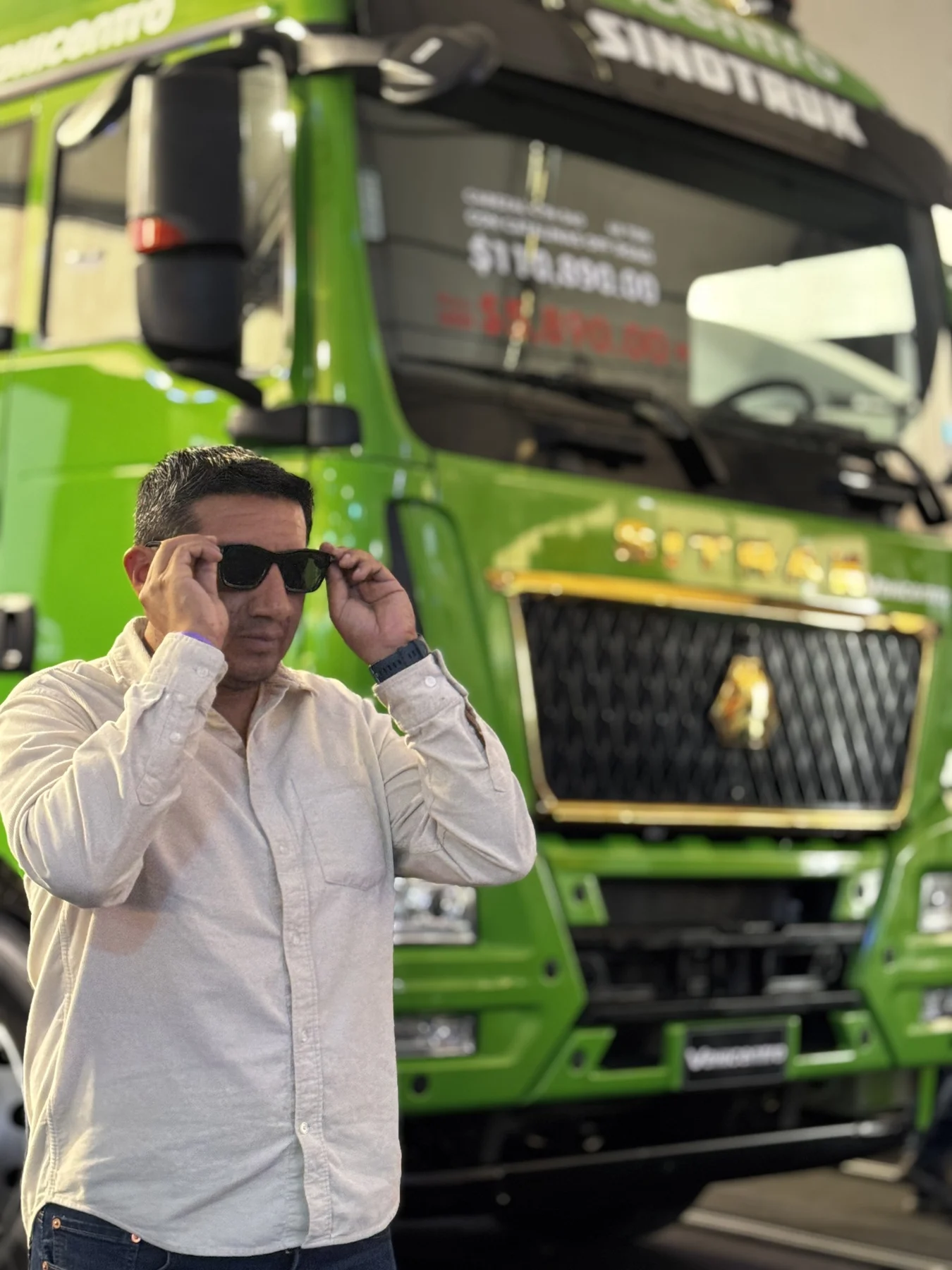 Miguel frente a un Sinotruk verde en una exposición